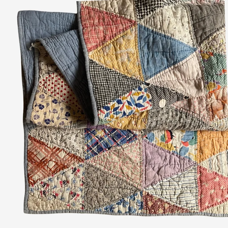 Collectible Pyramids quilt in soft pastel colors, geometric triangle pattern made from antique fabric pieces in pink, blue, yellow, green, and cream.
